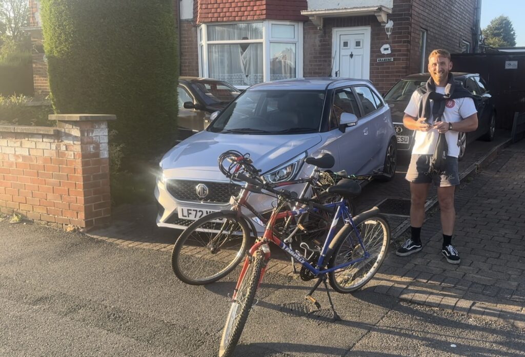 Louis standing with the two bikes on a driveway, before we head to the supermarket. 