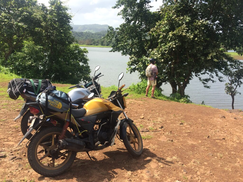 Image of 2 motorbikes in the Indian sun, with Louis taking a wee in the distance.